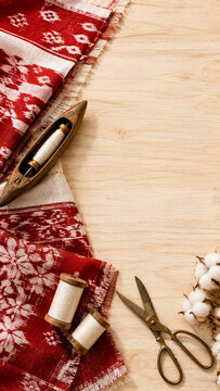 Traditional Indonesian batik textile with sewing tools on wood