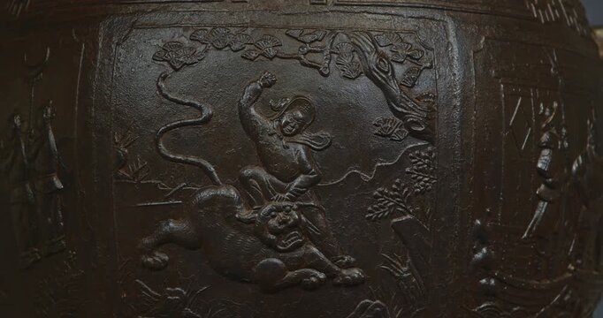 Chengdu, Sichuan, China. Ornate Iron Pot And Liu Bei Statue In Mausoleum Of Liu Bei, Wuhou Memorial, Three Kingdoms Temple. Depicts Scene Of Fighting With Tiger. Engraving On Bronze Incense Burial Pot