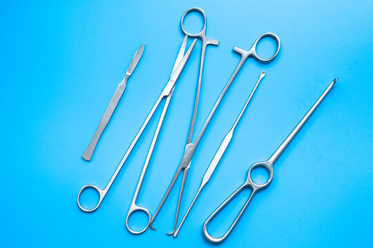A lot of stainless surgical instruments and tools on blue table, top view. Medical background