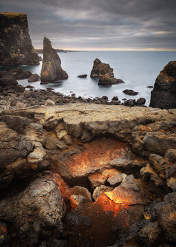 View of Valahnukamol coastal landscape featuring dramatic sea stacks, rugged volcanic rock formations, and a rocky shoreline in Reykjanesbaer, Iceland.