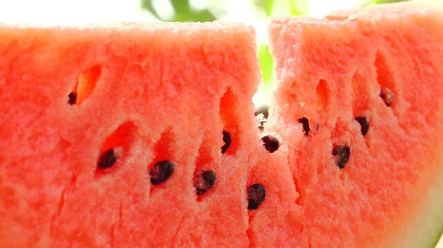 Watermelon slices reveal juicy red flesh and black seeds, showcasing the fresh fruit's vibrant colors and textures in natural light