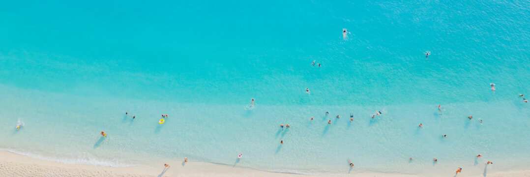 Aerial top view of tourists swimming and sunbathing in turquoise sea water near sandy shore Porto Katsiki beach Lefkada island Greece travel concept photo