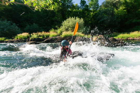 Kayaking on a white water river during daylight with splashes and strong currents