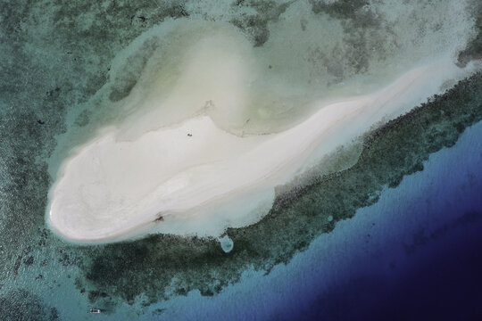 Aerial view of Nuha pasir putih, a pristine white sandbar surrounded by vibrant turquoise coral reefs and deep blue ocean waters in Adonara, East Nusa Tenggara, Indonesia.