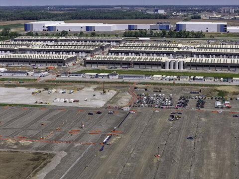 Aerial view of a large data center complex under construction with expansive industrial buildings, rows of cooling units, and a vast cleared site with parking areas in Indiana, United States.