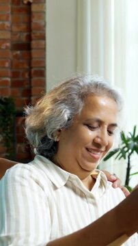 Indian Asian couple in their fifties with grey hair enjoying quality time together as they review a painting at home, with the wife holding a brush and the husband providing feedback