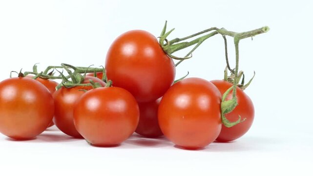 A bunch of cherry tomatoes on a white background, on a turntable.