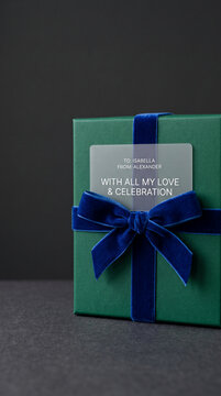 Green gift box with blue velvet ribbon and tag, symbolizing celebration and love, perfect for personal occasions or marketing.