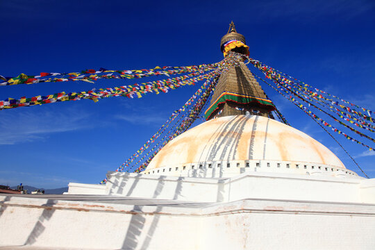 Boudhanath Stupa decorated with colorful Buddhist prayer flags against a deep blue sky in Kathmandu, Nepal