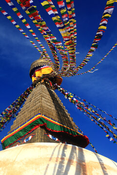 Boudhanath Stupa decorated with colorful Buddhist prayer flags against a deep blue sky in Kathmandu, Nepal