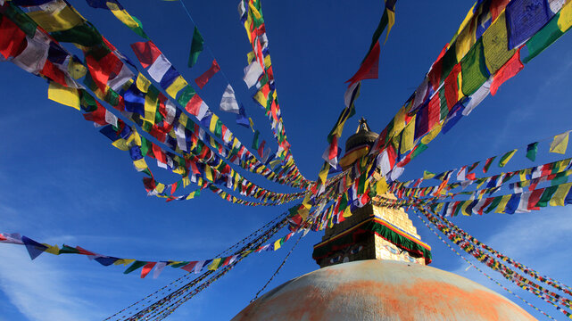 Boudhanath Stupa decorated with colorful Buddhist prayer flags against a deep blue sky in Kathmandu, Nepal