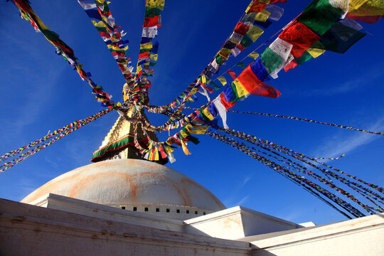 Boudhanath Stupa decorated with colorful Buddhist prayer flags against a deep blue sky in Kathmandu, Nepal