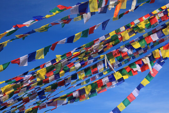 Colorful Tibetan Buddhist prayer flags fluttering against a clear blue sky, symbolizing peace, compassion, spirituality and Buddhist tradition