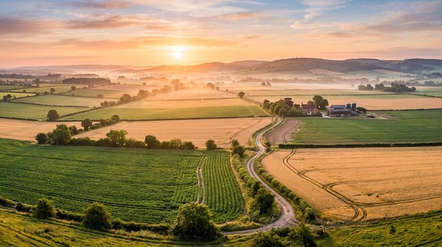 Aerial view of golden sunrise over peaceful English countryside farmland and rolling hills
