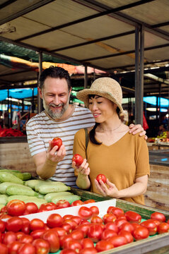 Couple Shopping at Outdoor Farmers Market Selecting Fresh Tomatoes &mdash; Asian Woman and Man Together