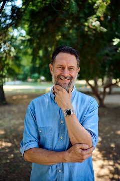Confident Middle-Aged Man Smiling in Park Portrait Wearing Denim Shirt for Lifestyle Branding