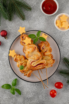 Puff pastry Christmas tree buns with cheese and ham on a plate. Christmas and New Year appetizer. Top view, copy space.