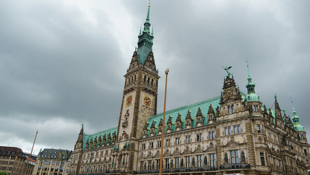 View of the historic Hamburg City Hall with its ornate clock tower and green copper roof under a cloudy sky in Hamburg, Hamburg, Germany.