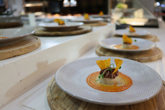 Plates of artfully arranged gourmet dishes captivate onlookers at a bustling restaurant. Each plate features innovative food designs and colorful garnishes.