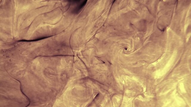 Golden amber liquid swirling in mesmerizing patterns creates a beautiful fluid motion animation suitable for high quality background textures or relaxing visual effects clips captured in this slow mot