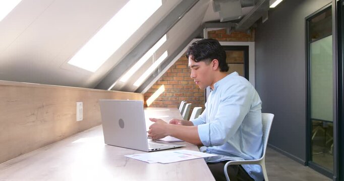 Glancing at papers for review, man typing on laptop, using pen, noting at counter, copy space