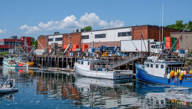 Commercial Fishing Dock in Massachusetts:  Fishing boats unload the day&rsquo;s catch while a transport truck waits on a dock in Gloucester, MA.
