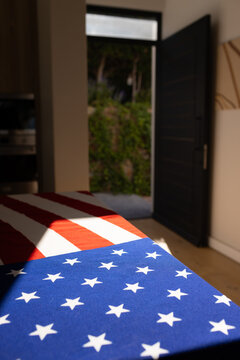 American flag draping across table with sunlight casting shadows and open door showing greenery
