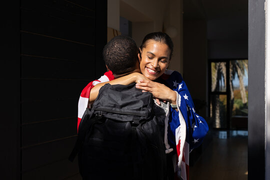 African American couple embracing in foyer woman wearing flag throw man wearing coat black backpack