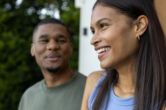 African American couple standing near white doorframe house entry, woman smiling in light blue top