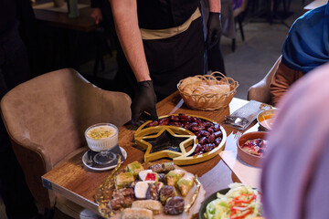 Obraz premium Muslim family shares iftar meal in a warm restaurant setting decorated for Ramadan celebration
