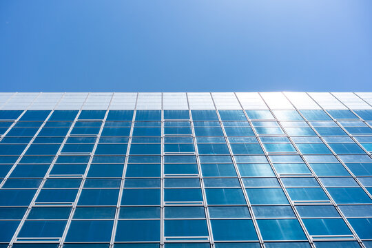 Glass Facade Office Building Under Blue Sky for Modern Architecture Corporate Vision and Real Estate Investment Background, Low Angle Perspective Photo with Copyspace