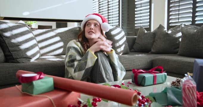 Adult woman opening eyes, sunlight coaxing, smiling in Santa hat, speaking at home showing wrapping