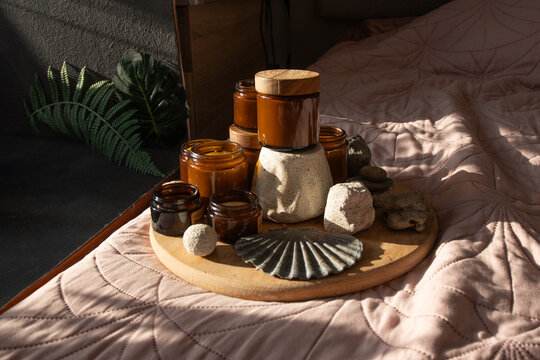 Candle Amber Jars with Wooden Lids on Bed. Candles Glass Jars and Bottles with Natural Elements.