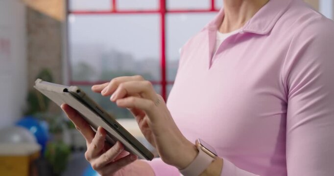 Middle-aged woman holding tablet, scrolling and tapping, prepping for therapy then posing in studio