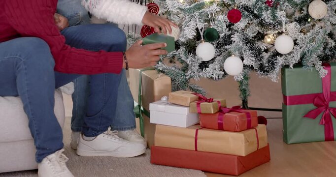 African American dad in Santa-hat watching as youth seeing gifts moving green gift by tree at-home