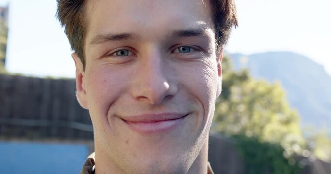Man facing camera, holding gaze while smiling, revealing teeth in backyard, collared jacket