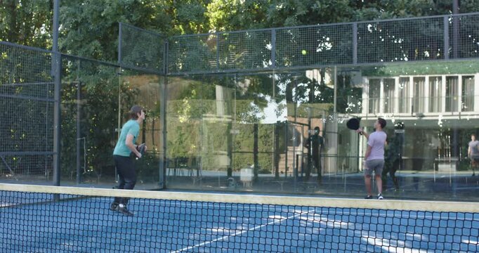 African American men rallying on court, left lunging after high lob to return ball with paddle