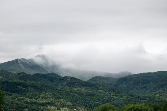 View of the lush green mountains shrouded in low-hanging clouds under an overcast sky in Posof, Ardahan, Turkiye.