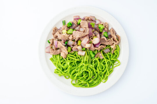A plate of spinach noodles tossed with beef and onions