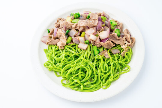 A plate of spinach noodles tossed with beef and onions
