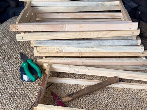 View of wooden beehive frames being assembled with wire and tools on a woven mat in Posof, Ardahan, Turkiye.