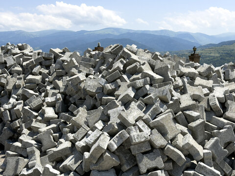View of a large pile of grey concrete paving blocks stacked outdoors with rolling mountains in the background in Posof, Ardahan, Turkiye.