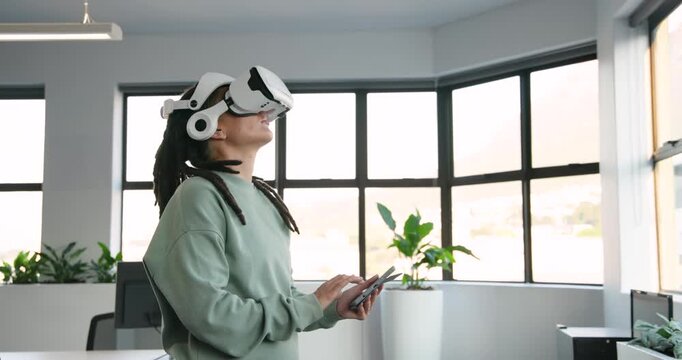 Non-binary African in white VR headset, mint top, looking up, tapping tablet testing VR in office