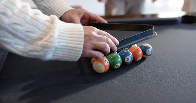 Diverse men racking balls at pool table to start game, African American man lining, striking shot