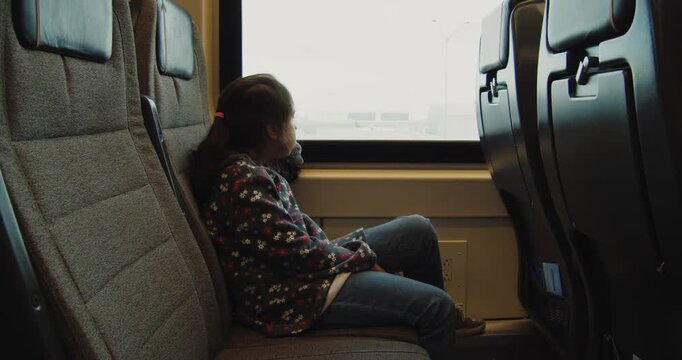 Girl looks out train window on journey to Toronto airport