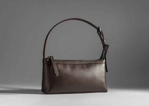 Classic dark brown leather baguette purse with shoulder strap in studio lighting