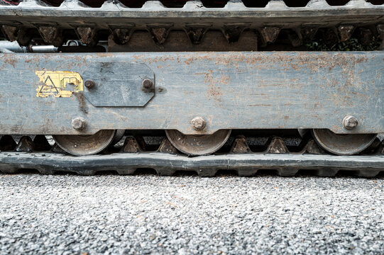 Abstract view of a tracked vehicle used for highway maintenance seen on an asphalt surface. The machine is a mobile mechanical excavator.