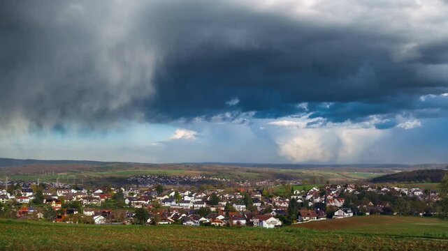 Weather time lapse with dramatic rain clouds over a scenic village. Dark rainclouds over the horizon of a rural countryside.