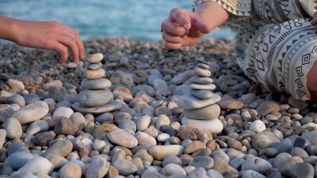 Two people are collecting pebbles on the seashore