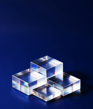 Crystal glass cubes podium stacked in staircase arrangement with rainbow light refraction on deep blue background